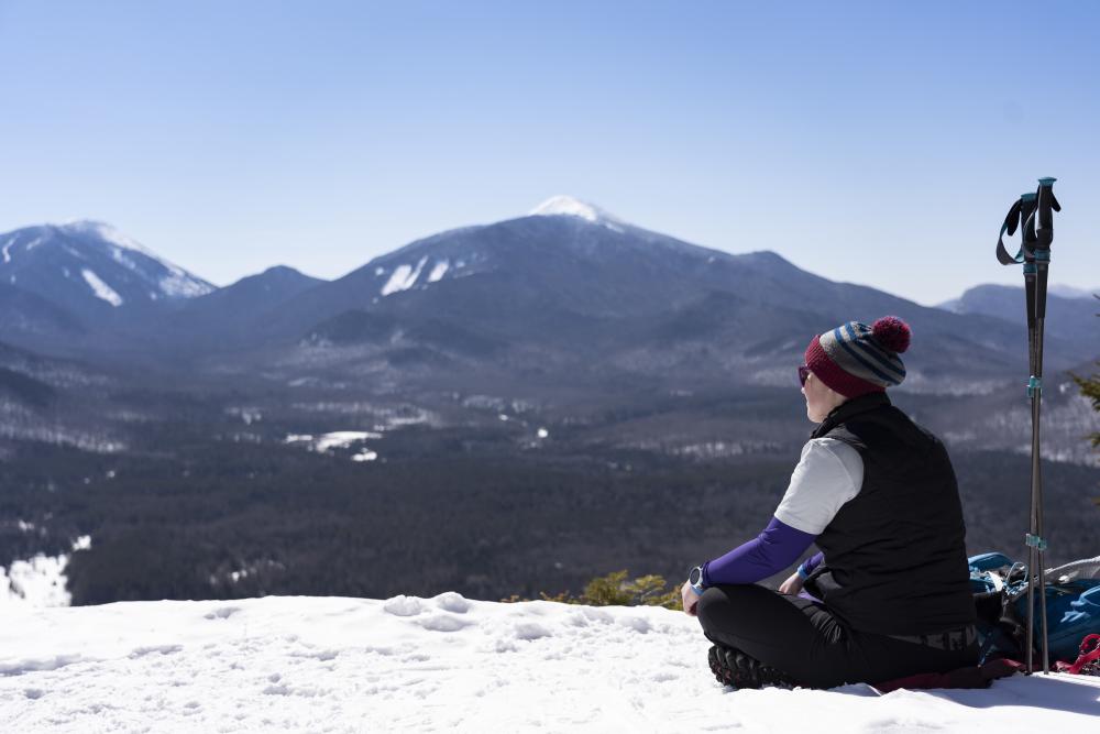 A winter hiker soaks up the view from the top of Mt. Van Hoevenberg in the winter.