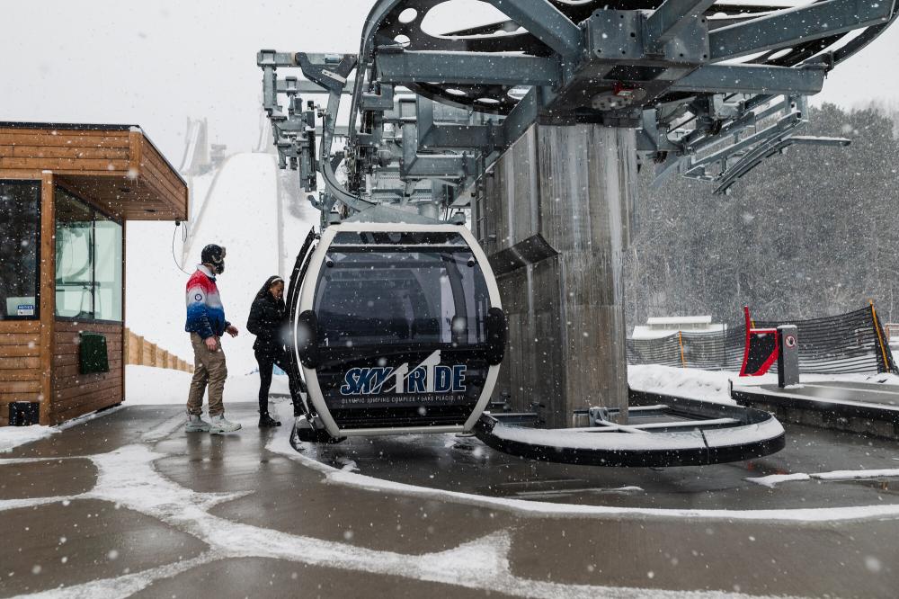 Two people hop on a gondola ride in the winter.