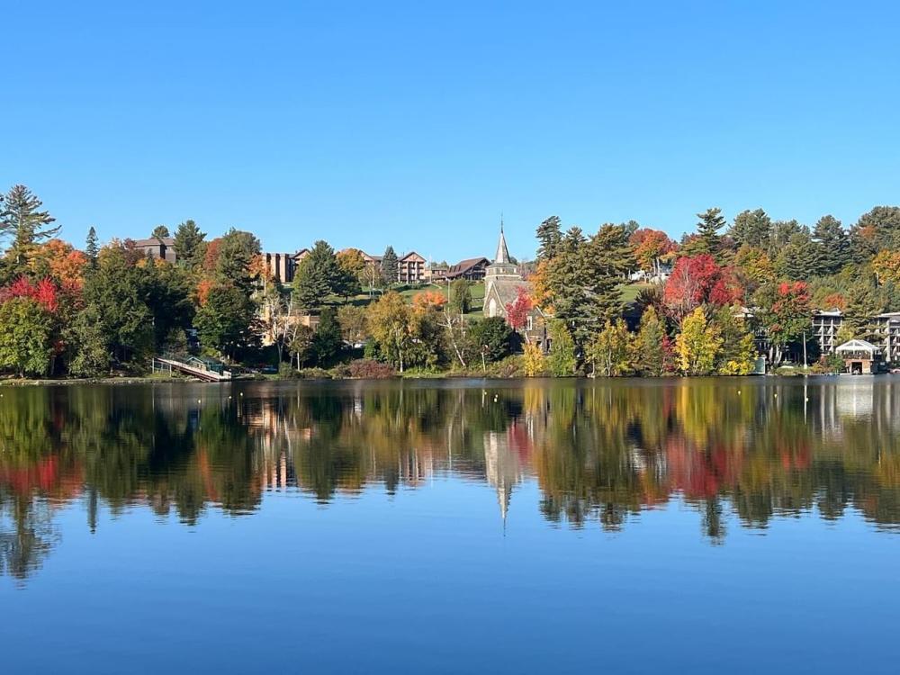 A view across the water of Mirror Lake during peak fall foliage