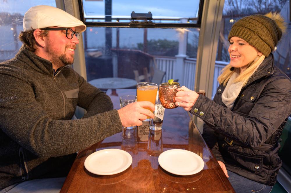 A couple cheers over the table inside the gondola seating at The Cottage restaurant.