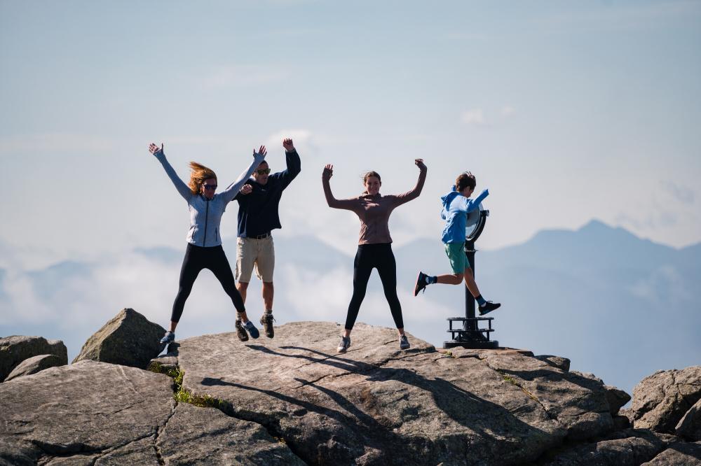 A family of four jumps on top of whiteface mountain.