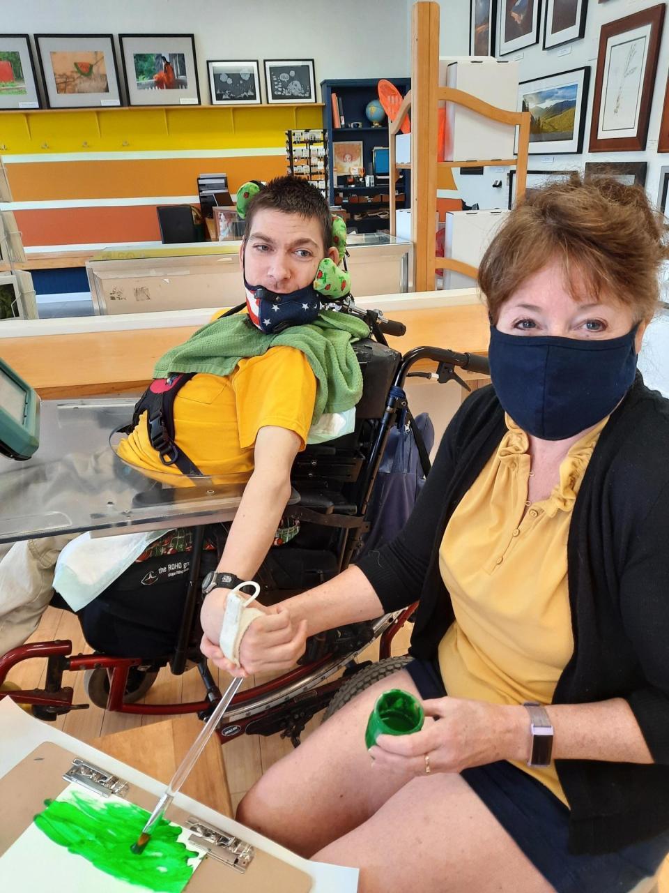 A man with a wheelchair and a woman paint together at ADK ArtRise studio in Saranac Lake