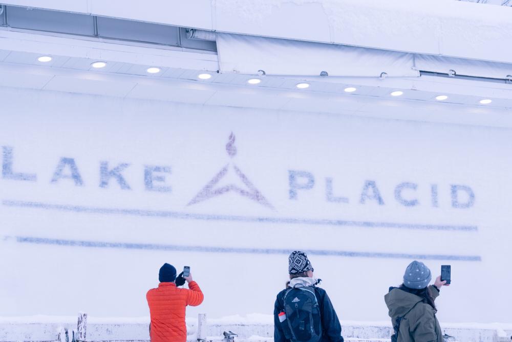 An icy bobsled track with the wording "Lake Placid" and people standing in front
