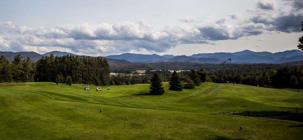 a mountain range with the Lake Placid ski jumps in the background and a golf course in the foreground.