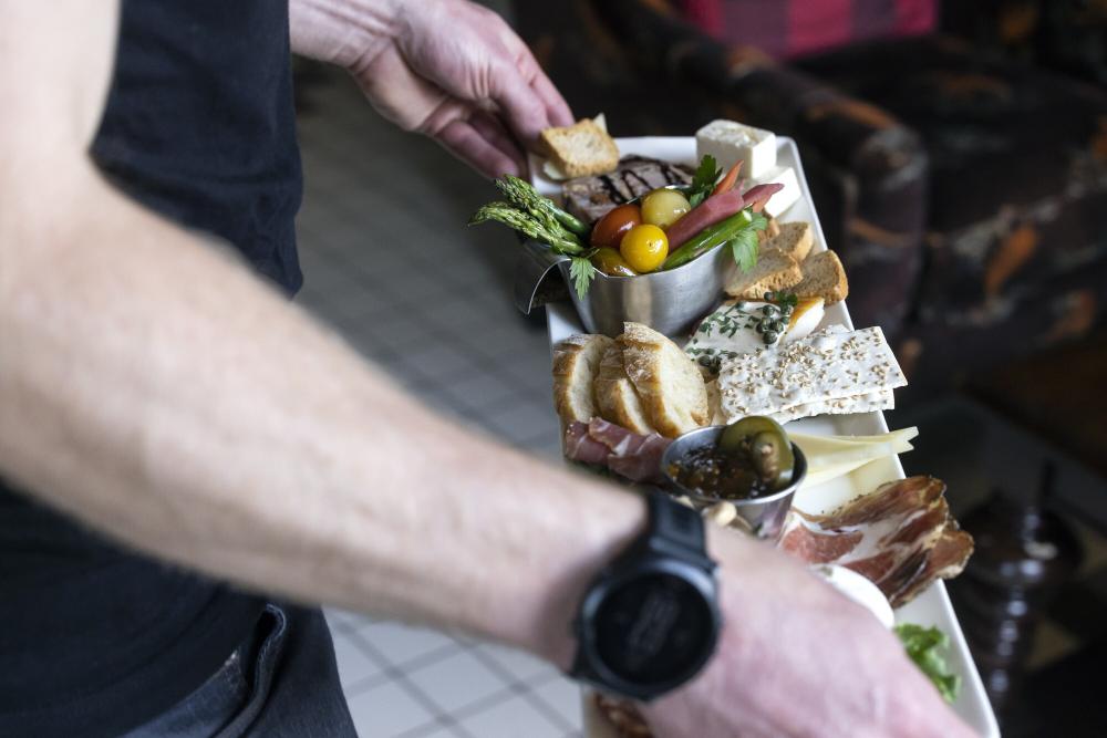 A close-up of a man holding a charcuterie board.