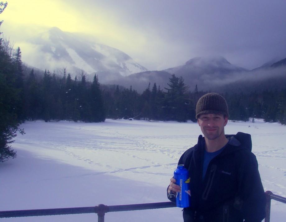 A skier takes a break at Marcy Dam (The terminus of the Whale's Tail Ski Trail)