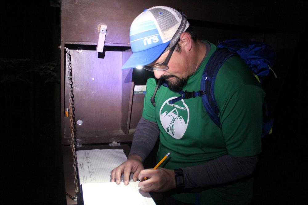 Dan signs the trail register by the light of his headlamp. Dan signs the trail register by the light of his headlamp.