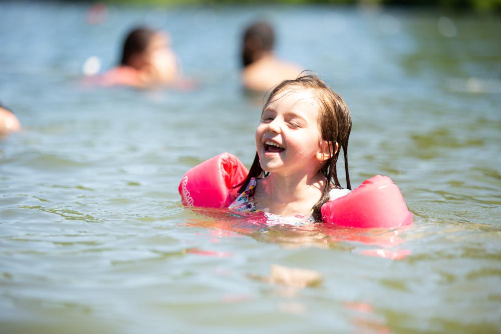 A girl in water wings laughs at the Mirror Lake Beach.