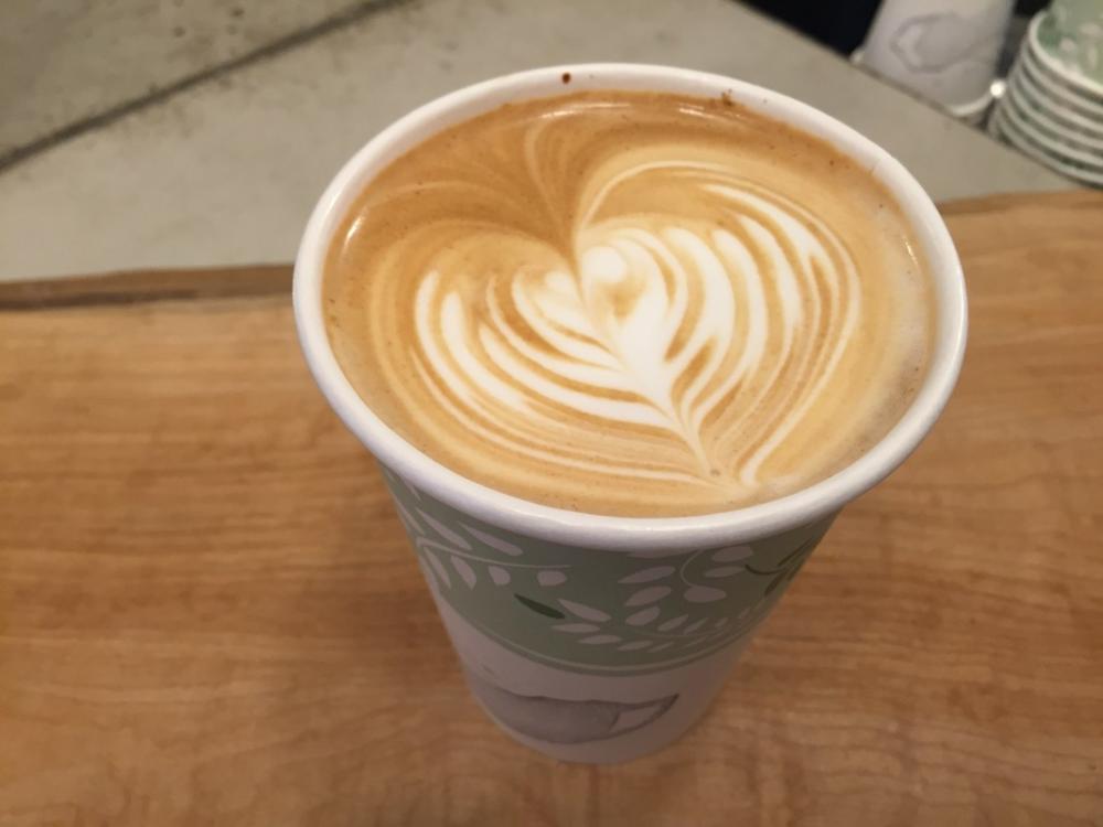 A latte in a paper cup on a table in one of Lake Placid's coffee shops