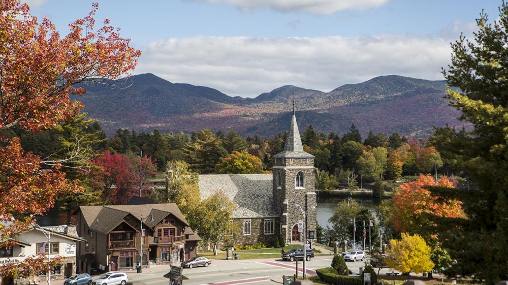 A scenic view of Mirror Lake and a local church amid fall foliage.