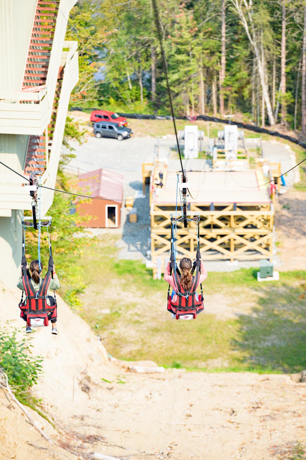 Two women descend a zipline.