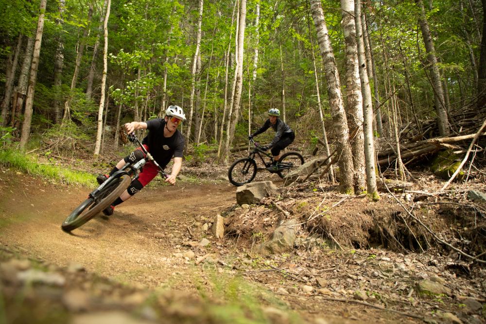 Two riders coming around a corner on one of Lake Placid's epic mountain bike trails