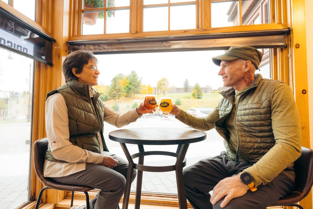 A man and woman cheers beers together at a brewery.