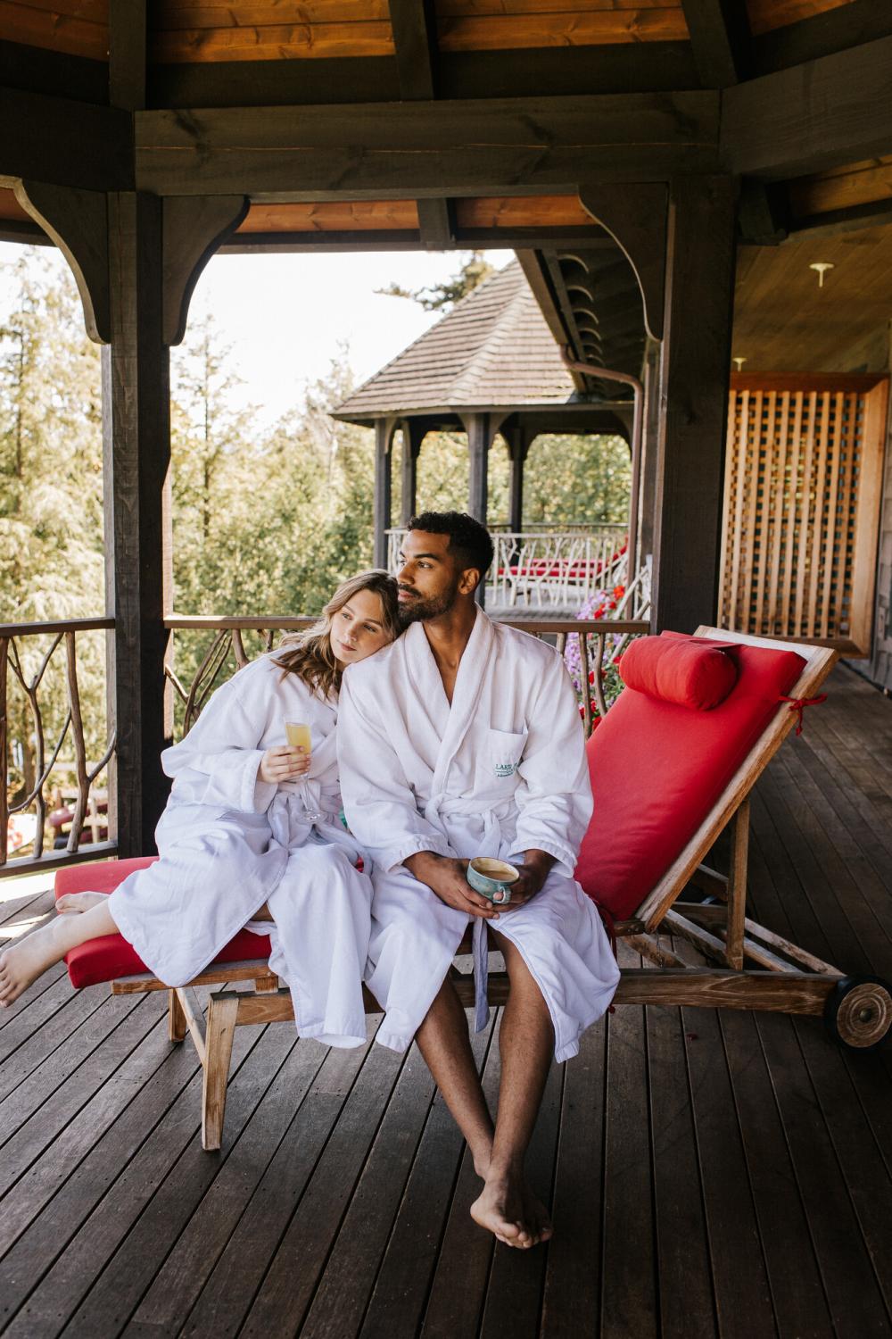 A man and woman sit in white robes at a resort.