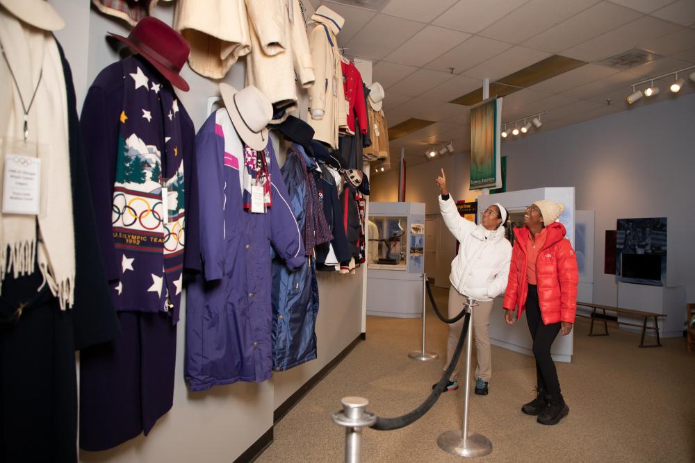 Two women admire historic uniforms at the Lake Placid Olympic Museum.