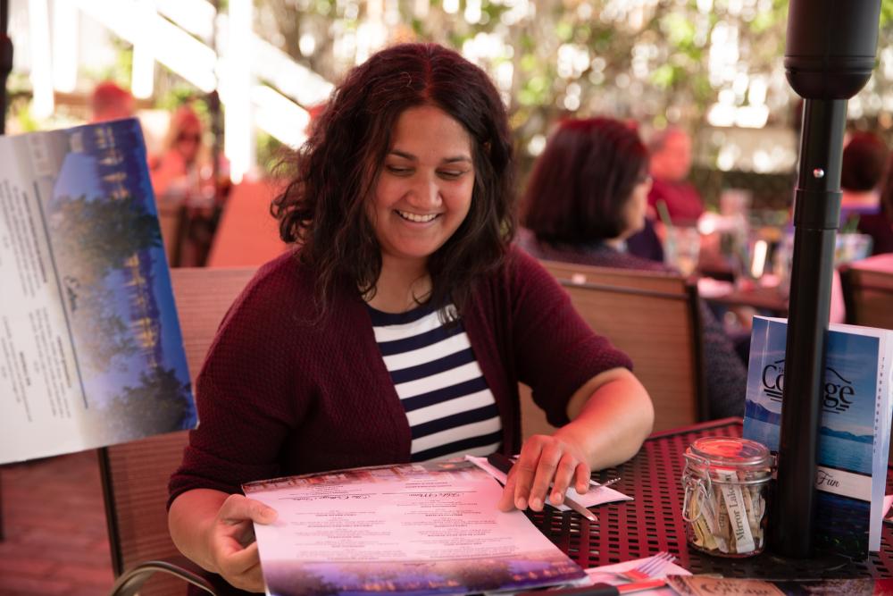 A woman studies the menu at The Cottage's outdoor dining area.