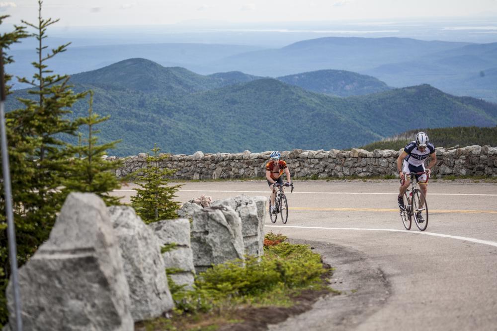 Two cyclists climb the Whiteface Toll Road.