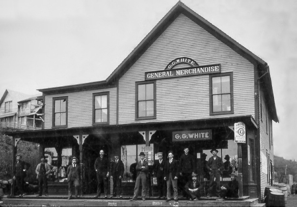 An antique black and white photograph of the general store in Newman, with men standing on the porch.