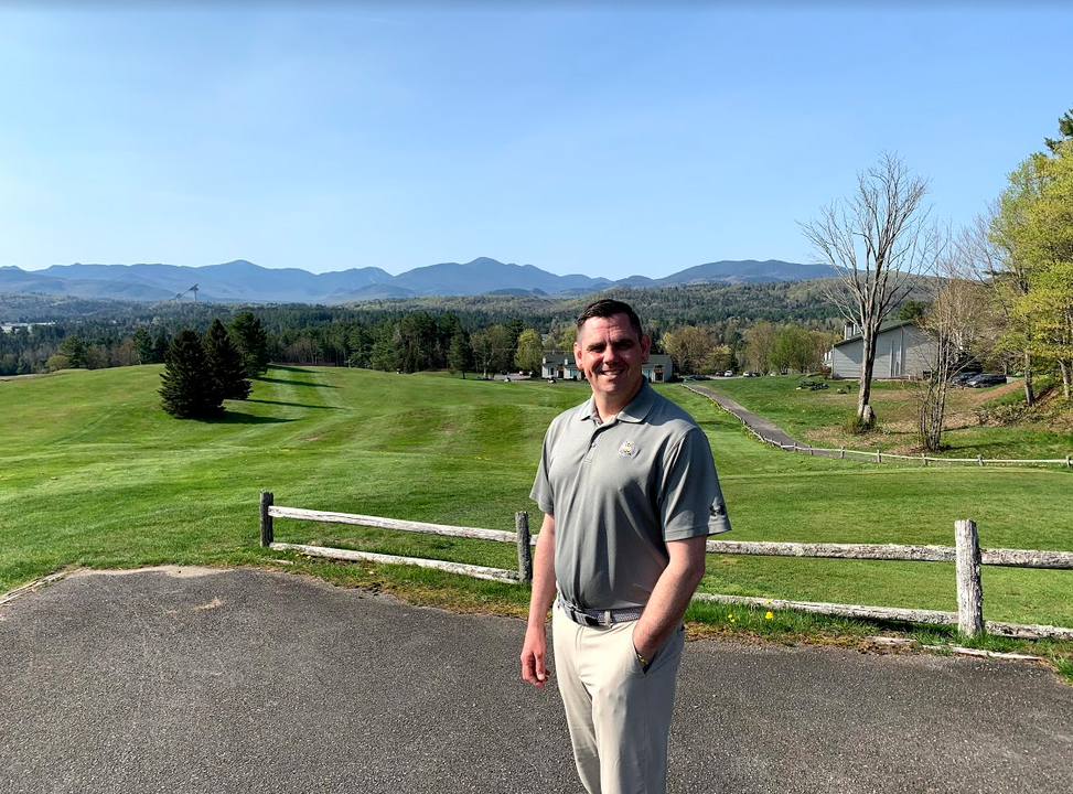 Lake Placid Club golf pro Jim Beauregard poses with the course and its Adirondack views behind him.