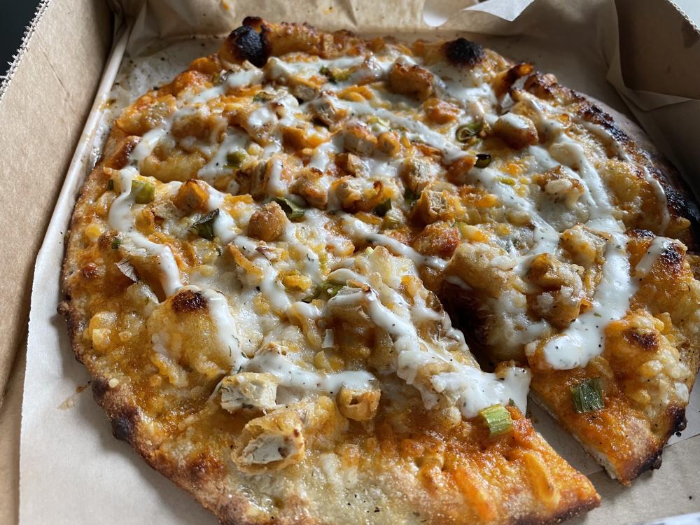 Vegan Buffalo "chicken" pizza baked with a drizzle of vegan "blue cheese" on top.