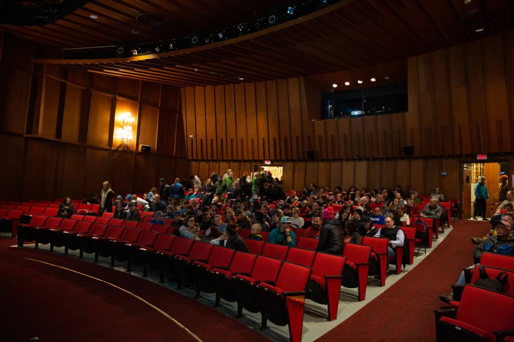 A seated crowd in a movie theater waiting for the show to begin