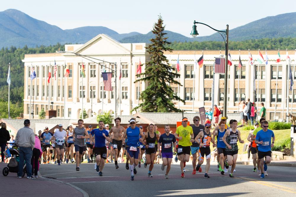 Runners race down a road as spectators look on.