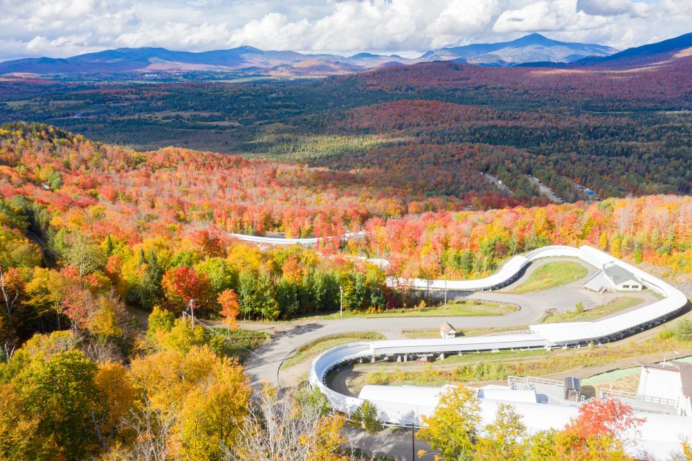 An aerial view of the bobsled track against a sea of colorful fall foliage.