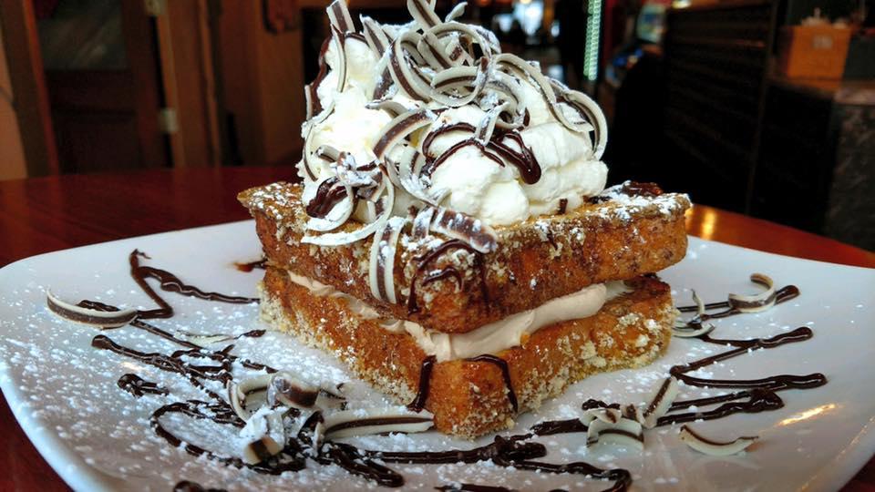 Now that's what I call French toast! Two pieces of French toast with creamy filling and topped with a big mound of frosting and chocolate curls.
