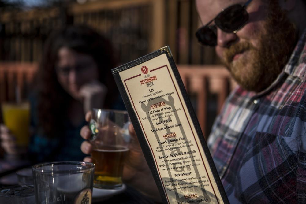 Man looks at menu with drink in his other hand
