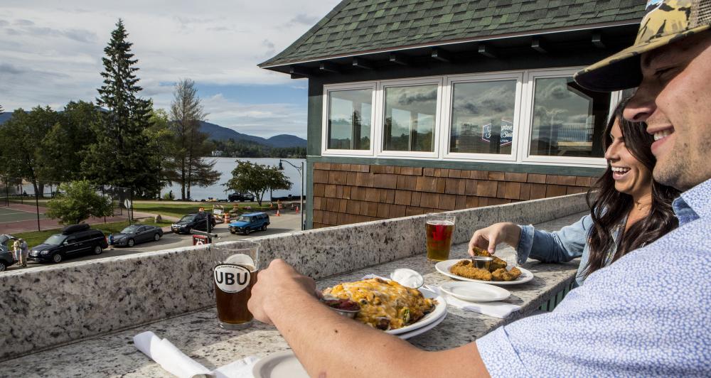 Two people sit with food on patio overlooking Mirror Lake