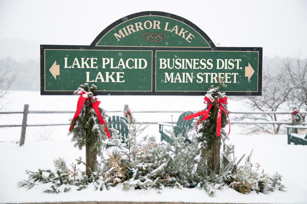 A snowy backdrop for the green Lake Placid Main Street sign.