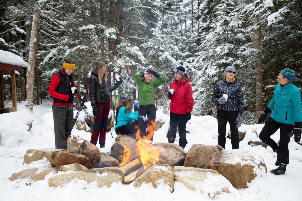 Group of women stand around fire in the snow