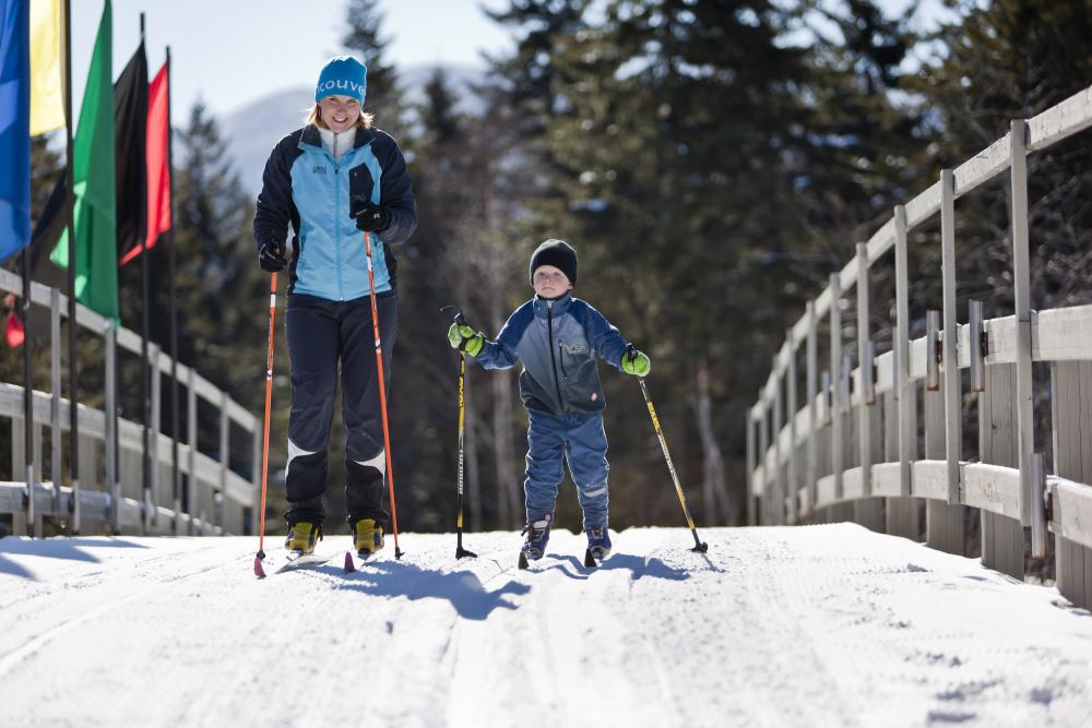 Mother and son cross country ski across bridge