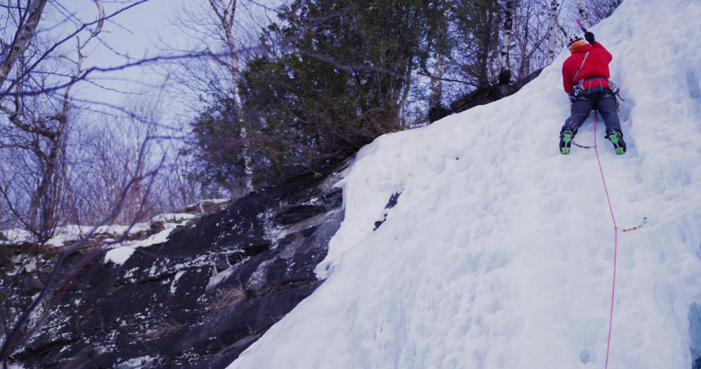 Man swinging ice axe on a wall of ice