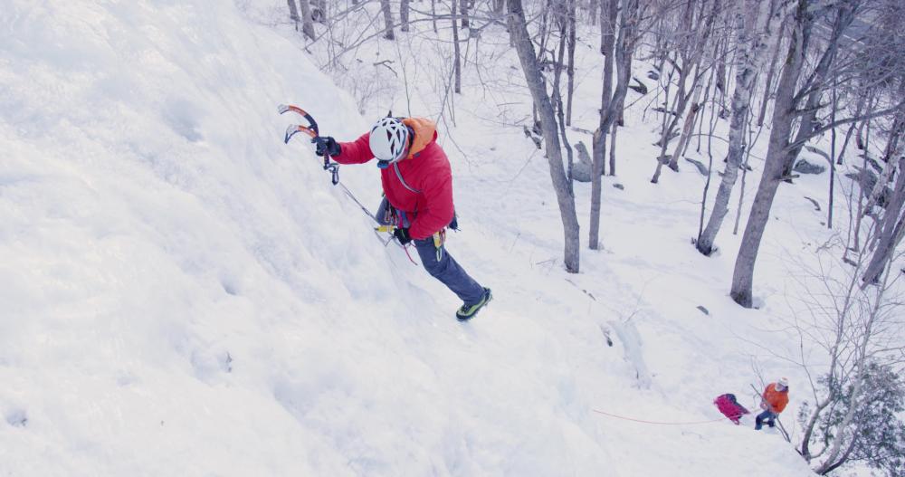 Man ice climbing with his belayer far below