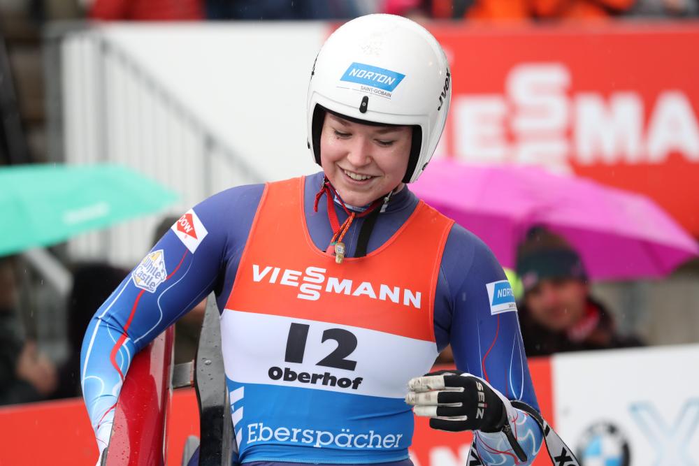 Ashley holds her sled and smiles after finishing her run.