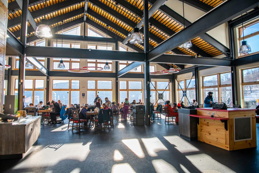 A large, open and airy dining room in the new lodge with lots of windows and happy diners.