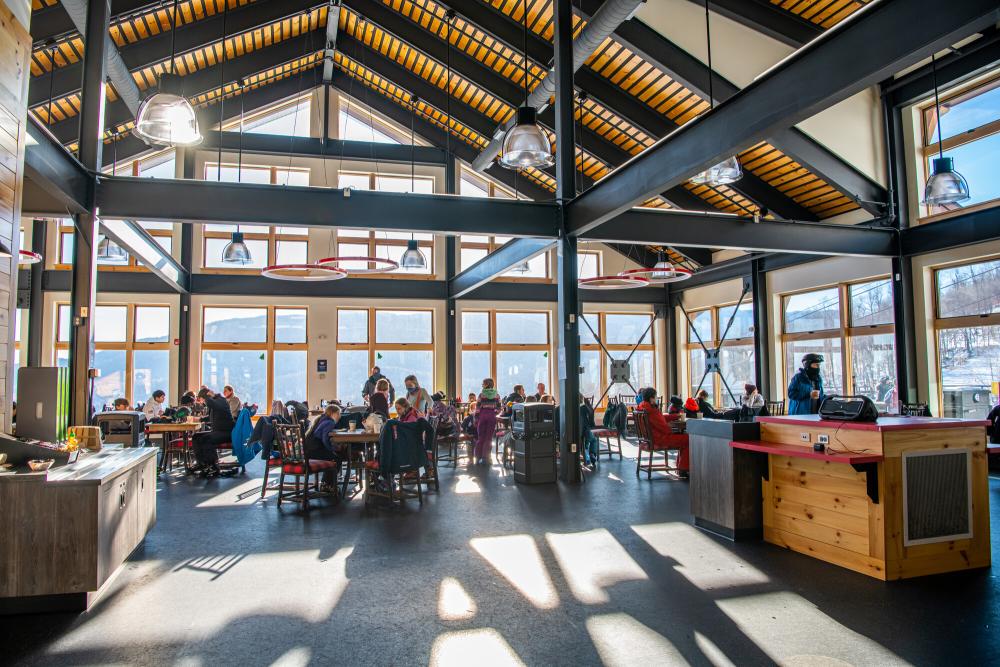 A large, open and airy dining room in the new lodge with lots of windows and happy diners.