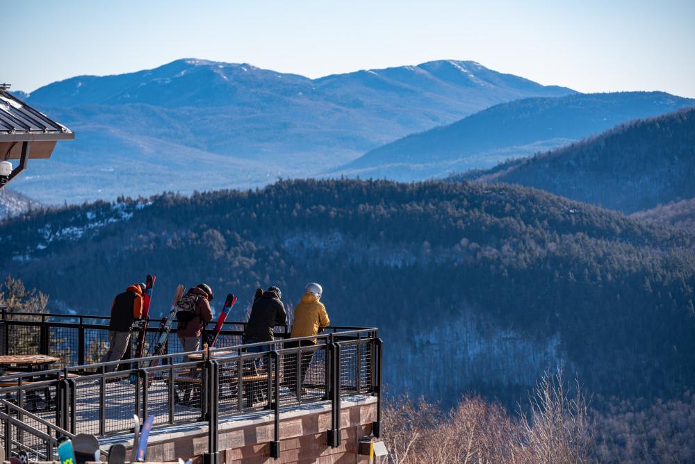 Four friends stand on a patio and look at the winter mountain views across the valley.