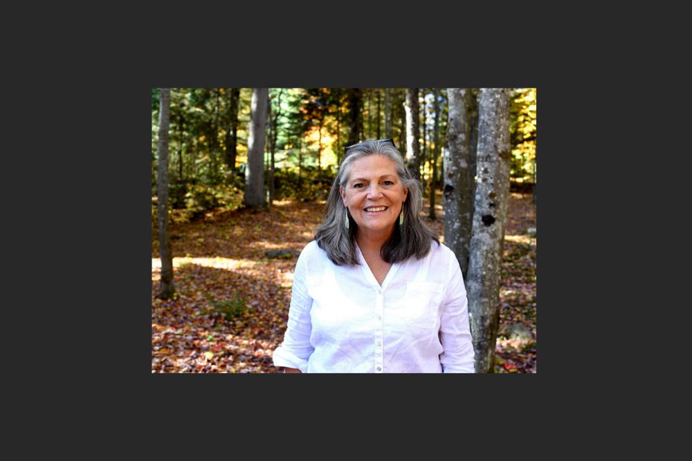 A woman smiling at the camera in the forest.