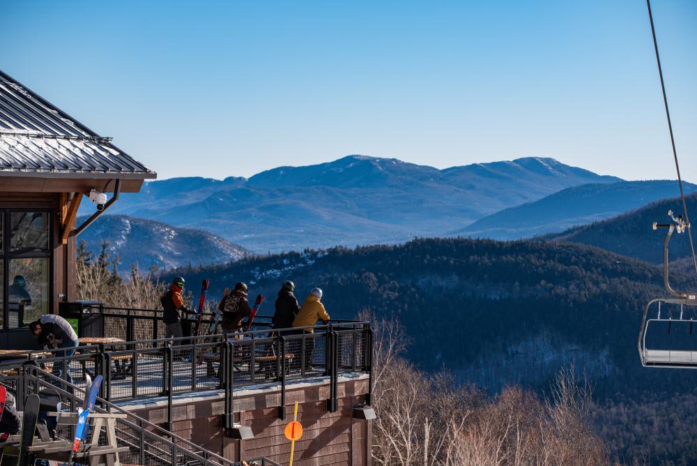 Group of friends hangs out on the porch of the midstation lodge with the mountains in the background