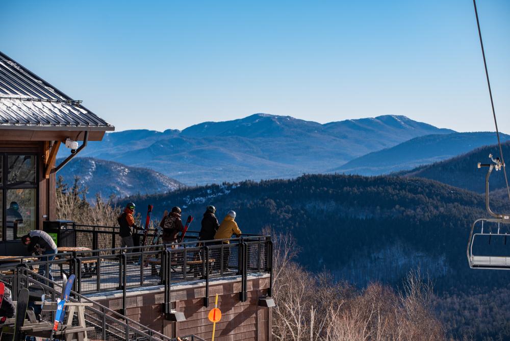 Group of friends hangs out on the porch of the midstation lodge with the mountains in the background