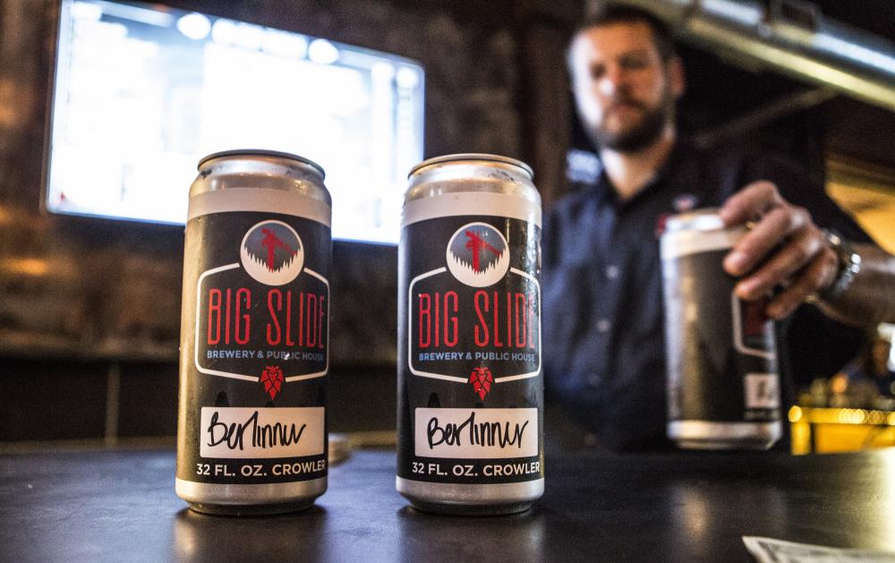 A bartender serves crowlers of beer for patrons to take home.