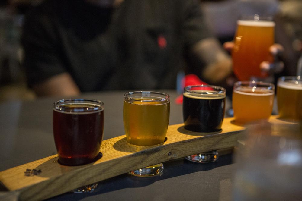 A flight of beers is served at the bar.