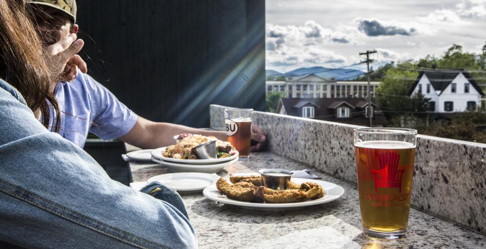 A couple eats on an outside deck with a view of the mountains in the background.