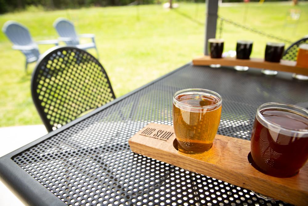 Flights of beers sit on tables outside.