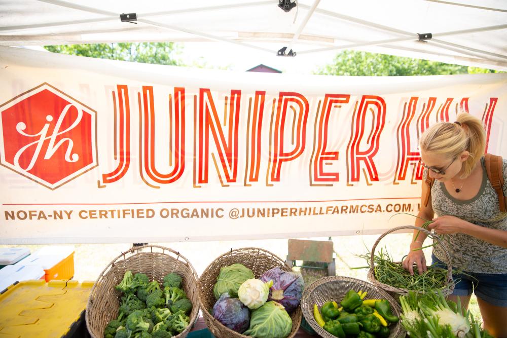 A woman picking out fresh vegetables at a farmers market.