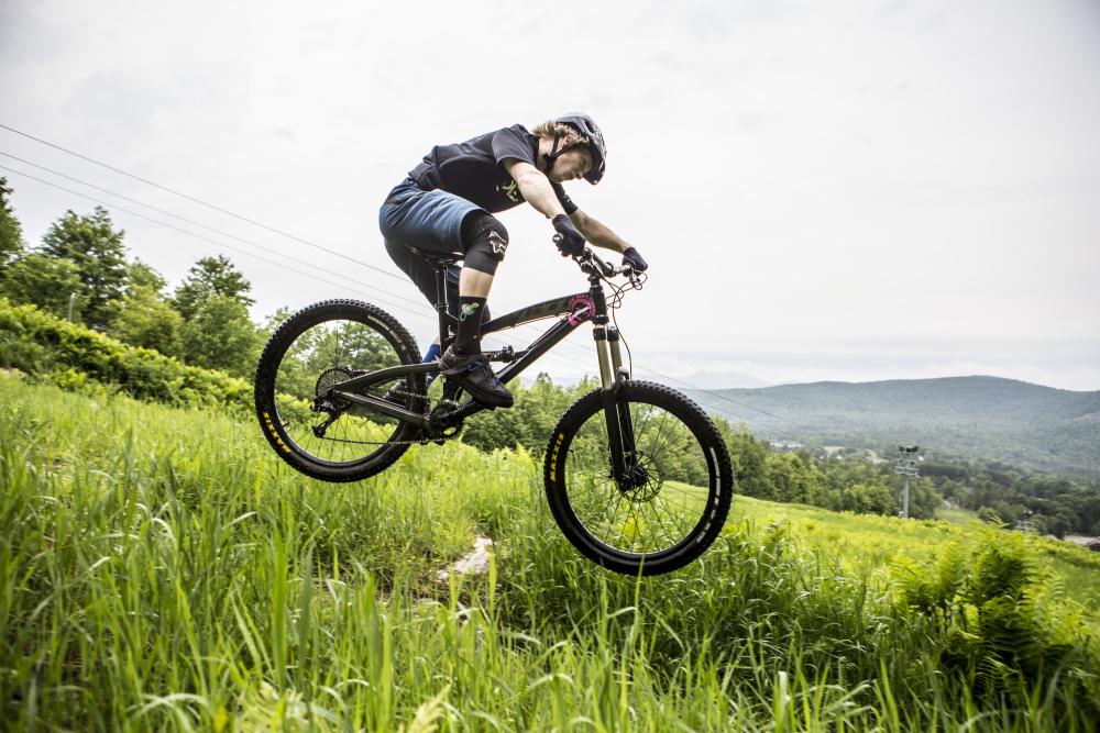 A person on a mountain bike descends a grassy hill.