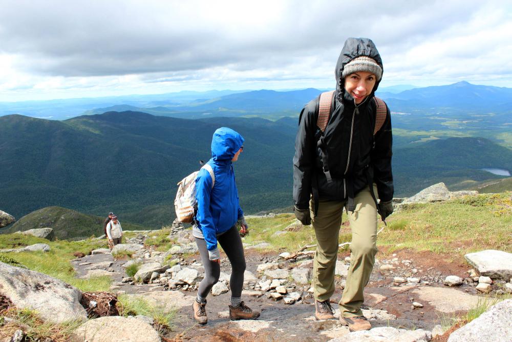 Four hikers climb a mountain with the high peaks in the background