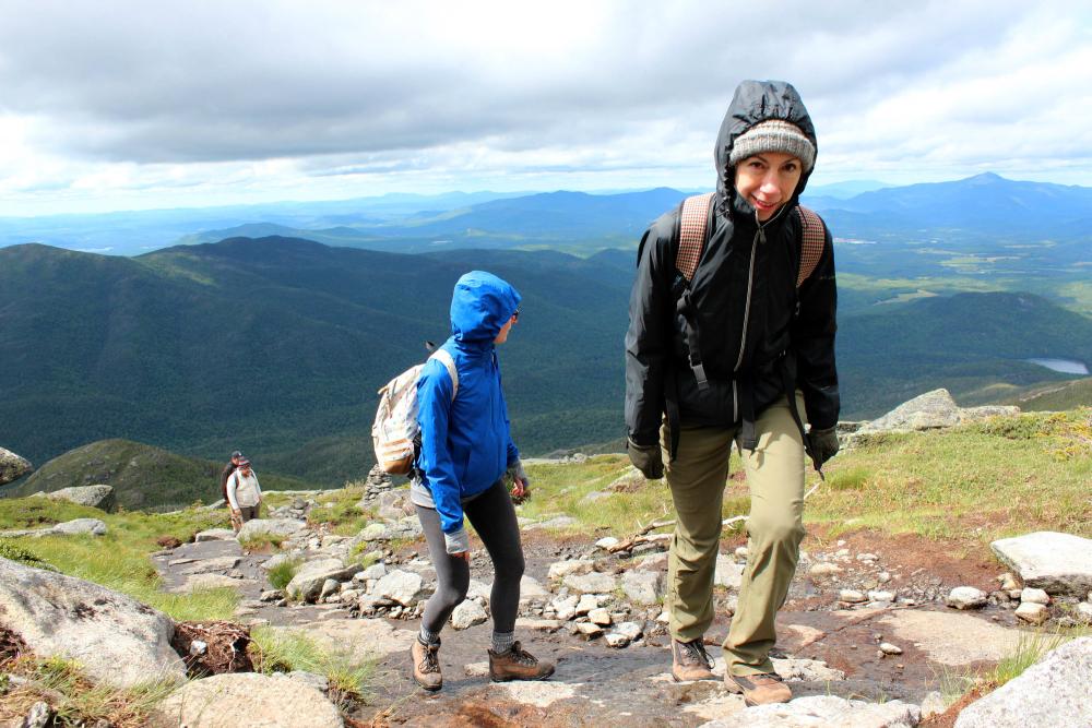 Four hikers climb a mountain with the high peaks in the background